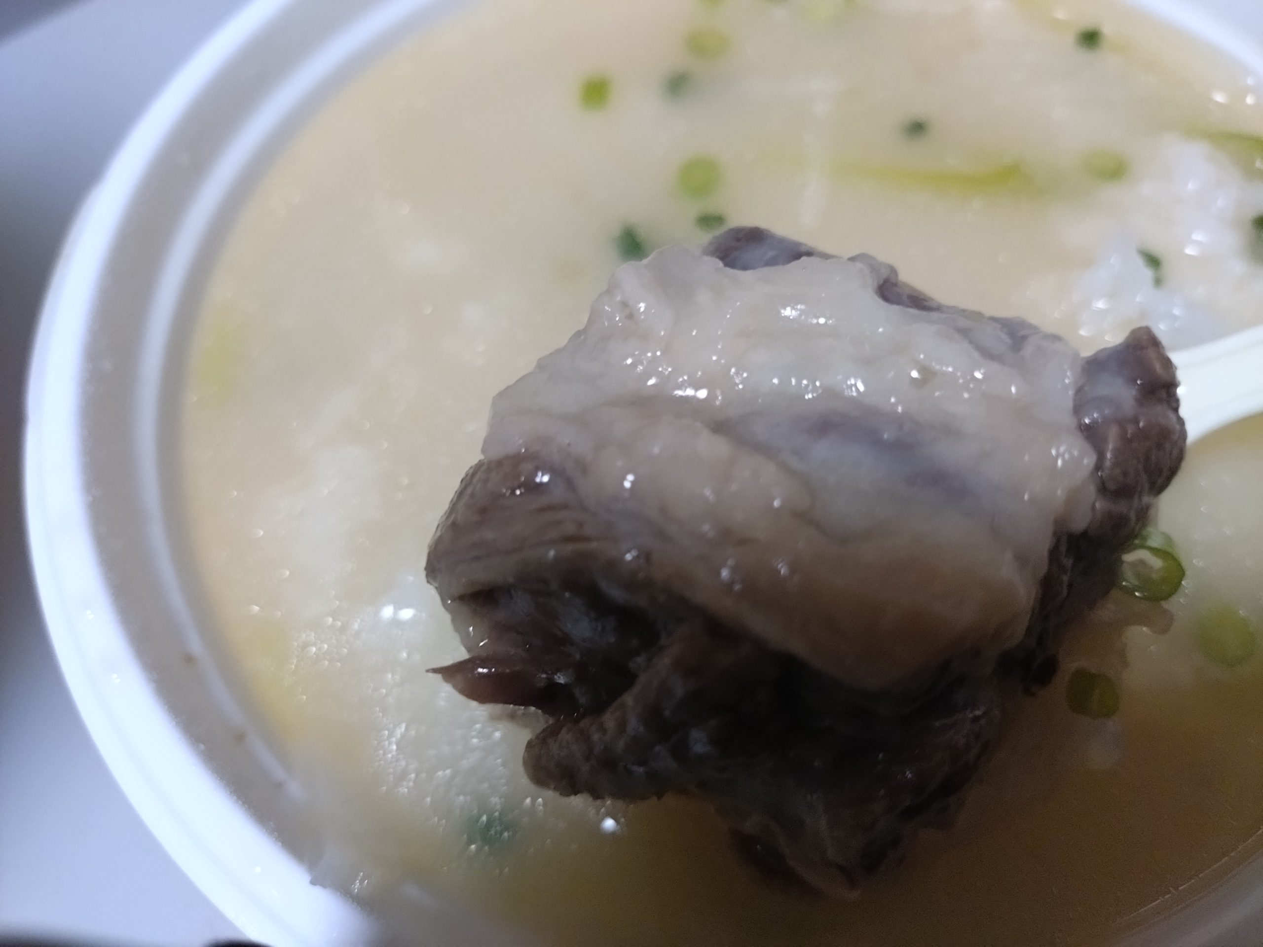 スプーンですくったコムタンスープの骨付き肉の塊