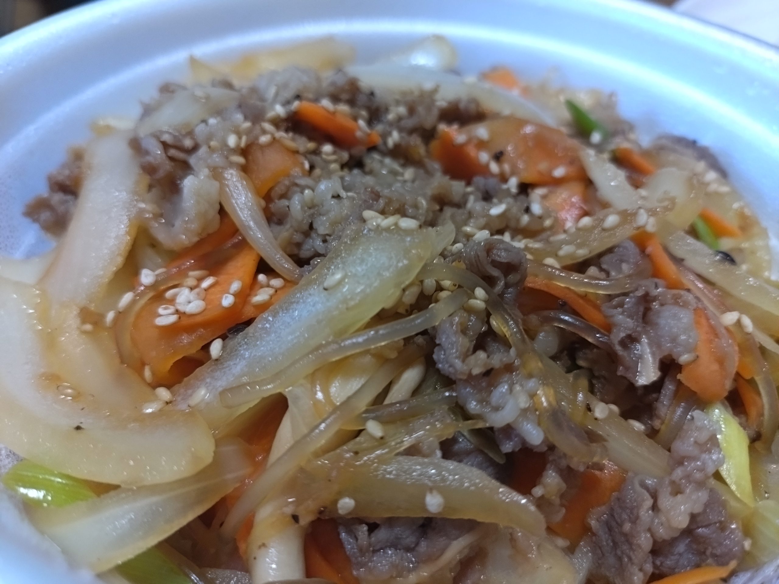 プルコギ丼の具材に寄った写真（牛肉、玉ねぎ、にんじん、白ごまなど）