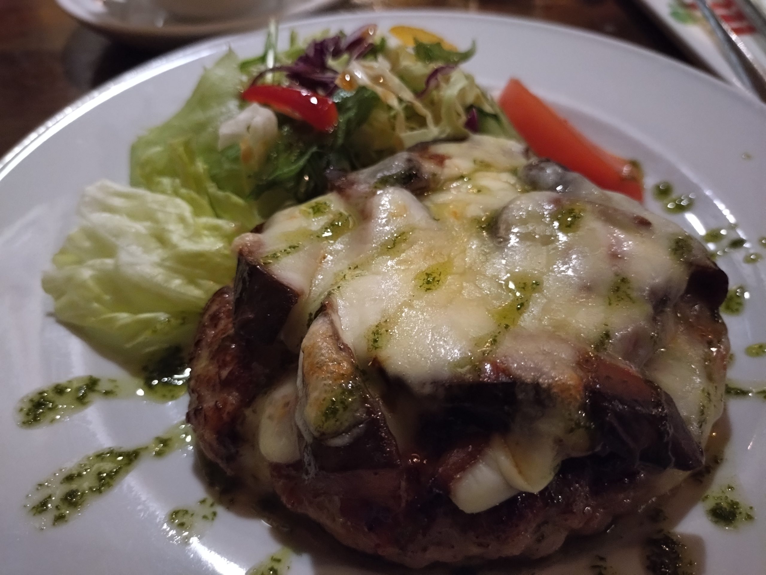 なすのチーズ焼きハンバーグ|アップ なすのチーズ焼きハンバーグのアップ。とろけるチーズとなす、粗挽きの肉感が見える。