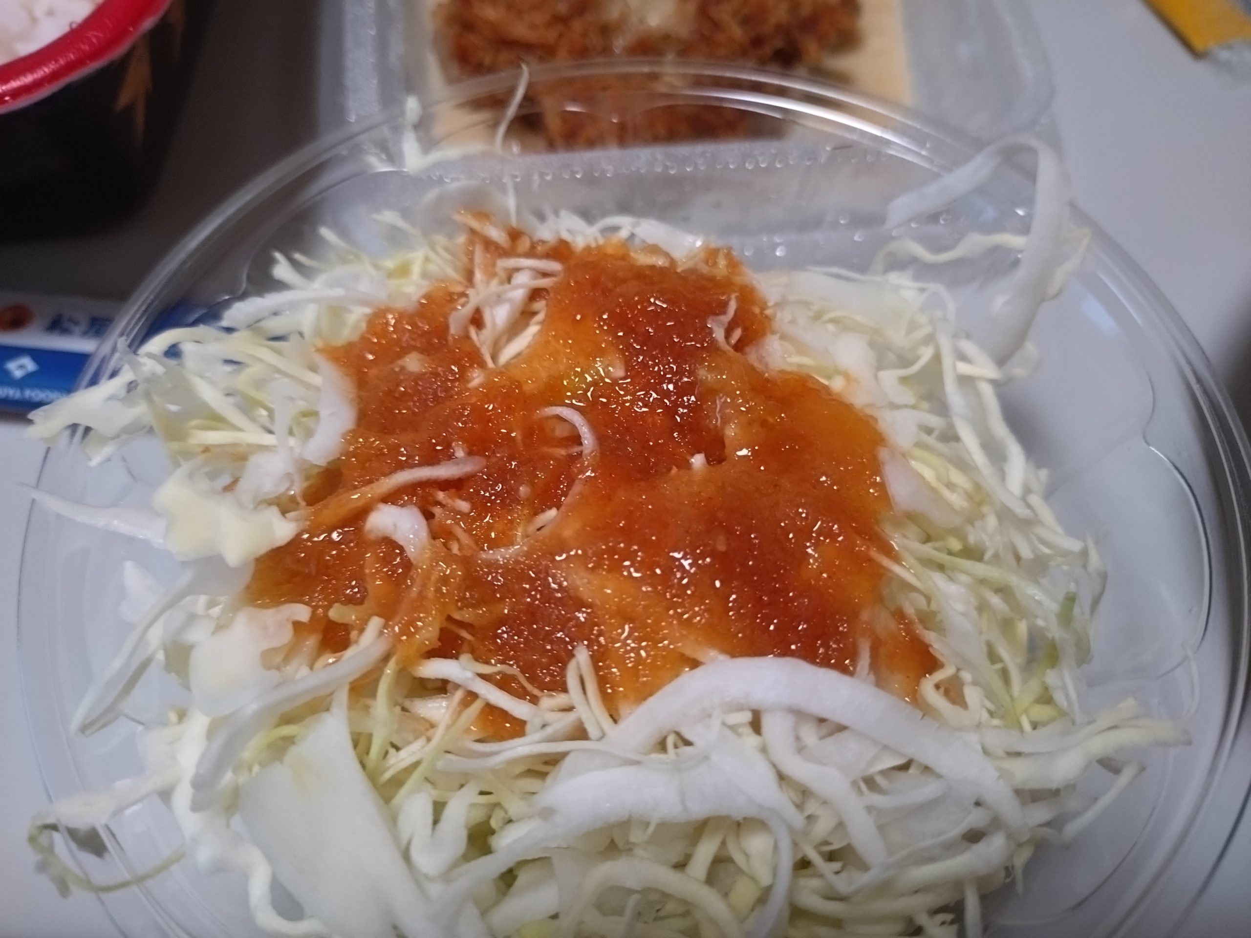 フタを閉じた状態のシュクメルリチキンかつ定食容器。白いソースが多く、深さのある容器が使われている