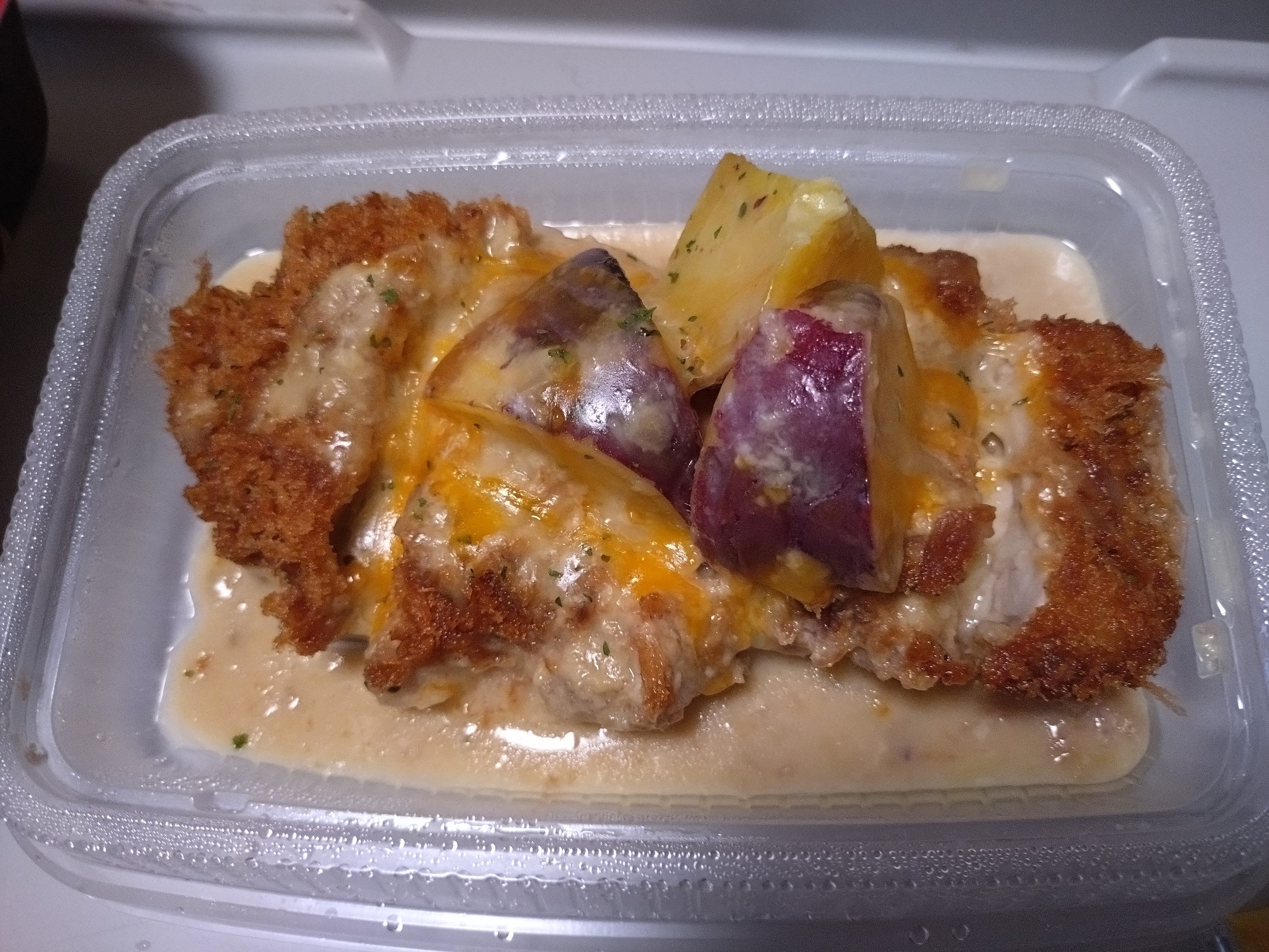 フタを開けた直後のシュクメルリチキンかつ定食。白いソースにチキンかつとサツマイモが浸かっている