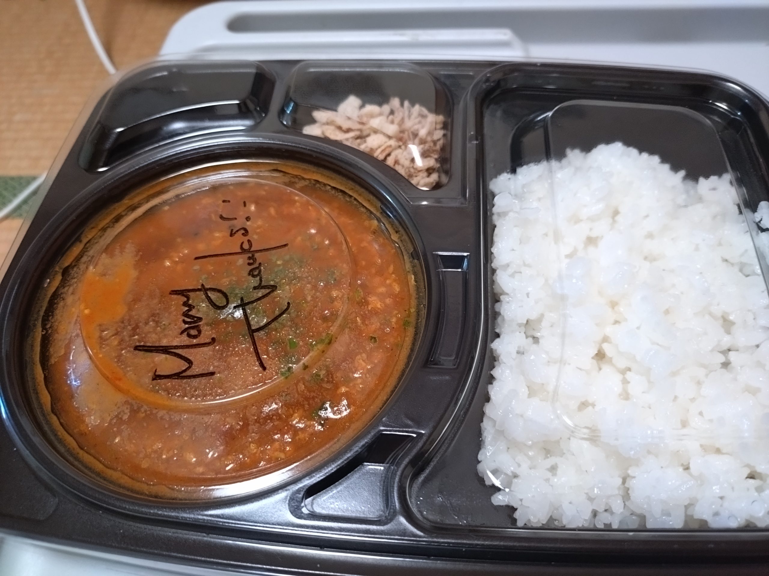 旨辛スパイスキーマカレーのテイクアウト容器を開けた状態。ご飯とカレーが別れている