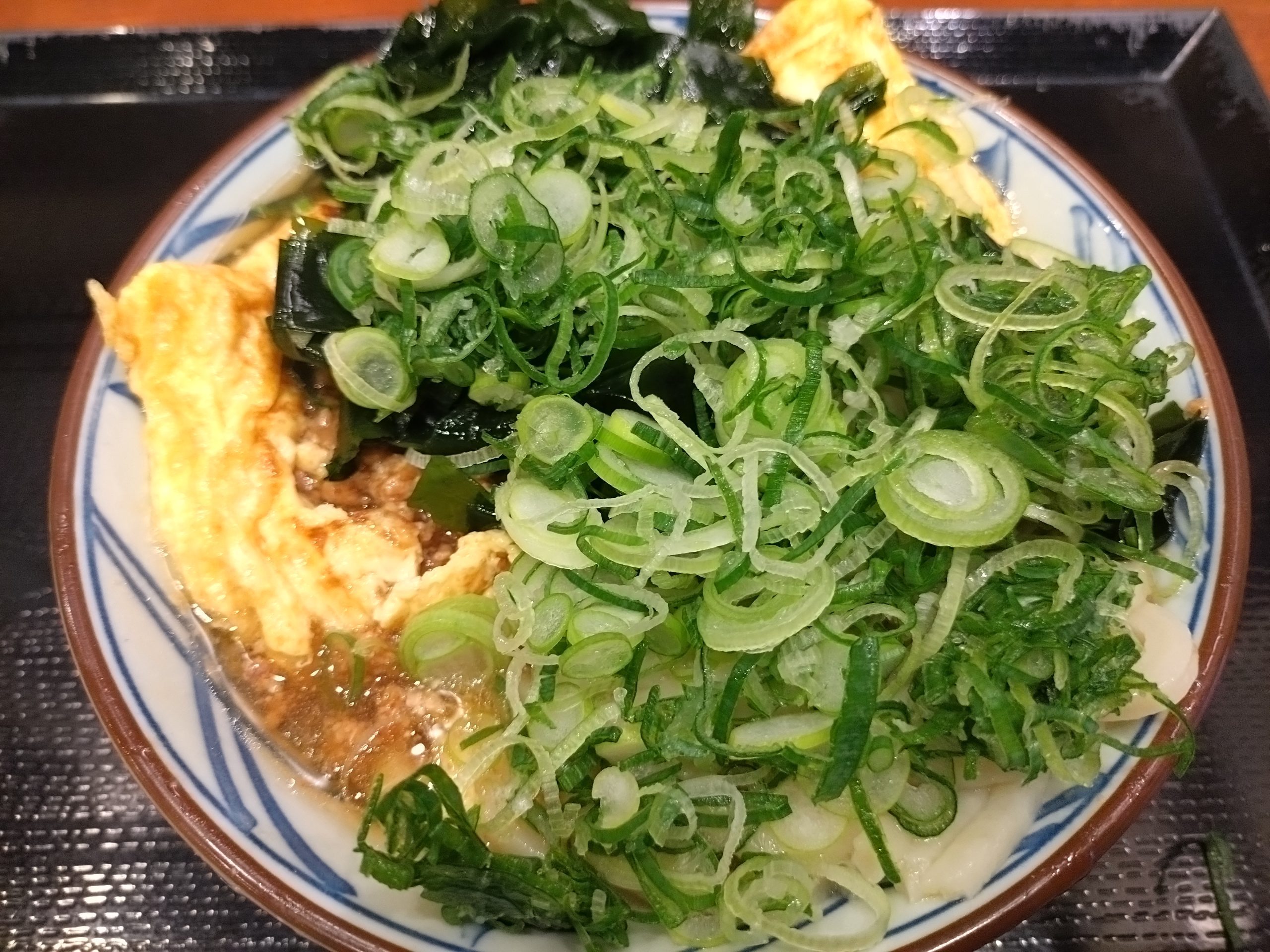 ネギとわかめを多めにのせた玉子好きのための肉づつみうどん
